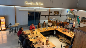 Asistentes sentados alrededor de una mesa preparada con platos de quesos y copas.